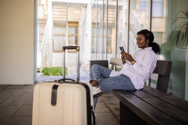 istock Woman Black ethnicity using mobile phone while waiting for her transportation at the station 1390843829