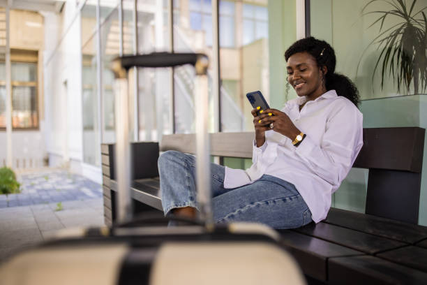 istock Woman Black ethnicity using mobile phone while waiting for her transportation at the station 1390844131