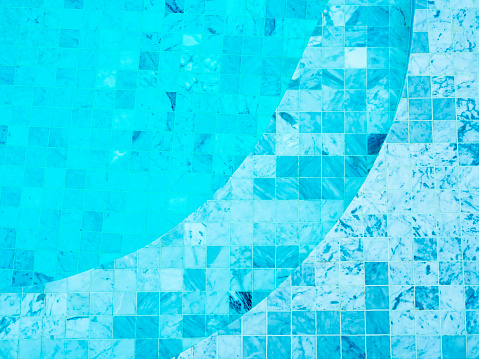 Mosaic grid pattern background with curved steps in blue water surface in the swimming pool background, top view. Empty blank space for summer background, vacation time, holiday concept.
