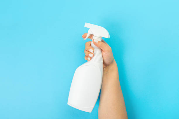 istock Housewife's hand holds a spray with cleaning agent on a blue background. Detergent for various surfaces in the kitchen, bathroom and other rooms. Close-up. Light pastel blue background. 1390848291