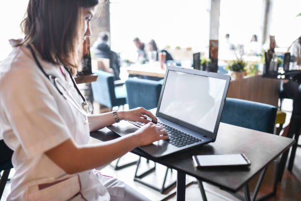 istock Nurse Using Laptop For Electronic Banking While Sitting In Coffee Bar 1390848970