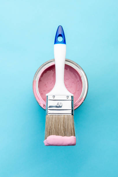 istock Brush on open can of pink paint on blue pastel background 1390850035