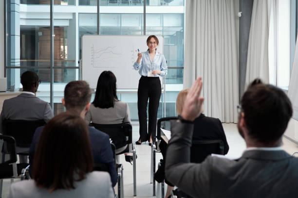 istock Young smiling female lecturer questioning audience after presentation of data 1390852829