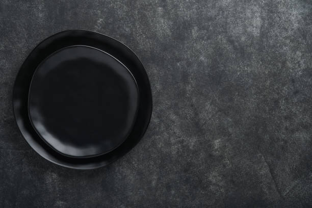 istock Ceramic empty black plate on old black ceramic cement concrete table background. Cooking stone backdrop. Top view with copy space. Flat lay 1390856740