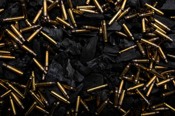 istock Empty shells from weapons on black smoldering coals. Consequences of the war. Dark background. 1390857705