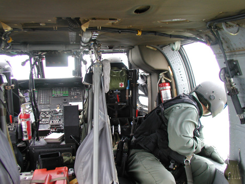 Interior of a UH-60 Blackhawk with a jumpmaster sitting by the door on the way to the dropzone.