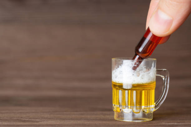 小さな瓶から木のテーブルの上に置かれた小さなビールマグカップにビールを注ぐ。適度なアルコール消費の概念。 - beer bottle beer drinking pouring ストックフォトと画像