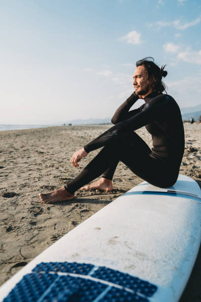 istock A man is sitting on his surfboard on the beach 1390861677