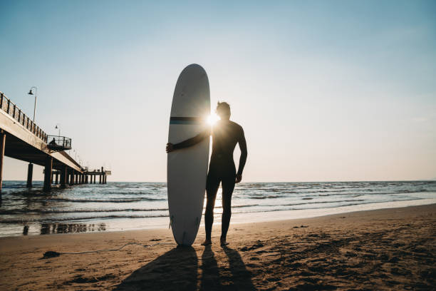 istock A man is standing on the beach with his surfboard, admiring the sunset 1390861708