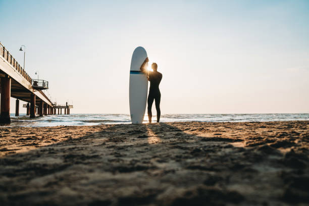 istock A man is standing on the beach with his surfboard, admiring the sunset 1390861721