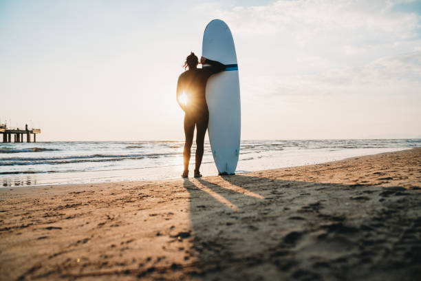 istock A man is standing on the beach with his surfboard, admiring the sunset 1390861727