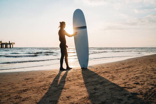 istock A man is standing on the beach with his surfboard, admiring the sunset 1390861730