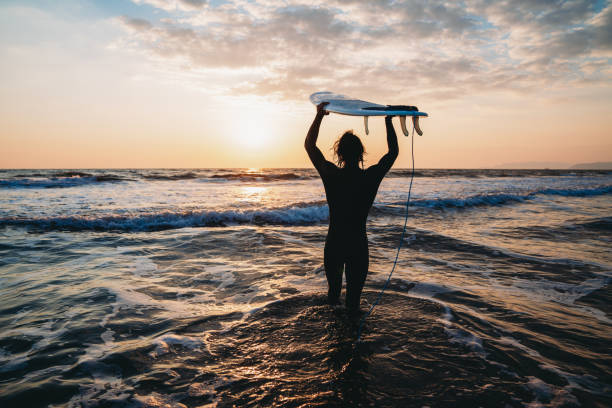 A man is holding his surfboard above his head. He's ready to go surf.