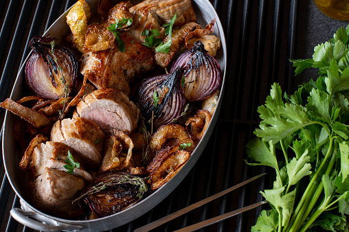 Delicious roast pork fillet with caramelized and deep fried onions. Served in a rustic roasting pan on dark table background