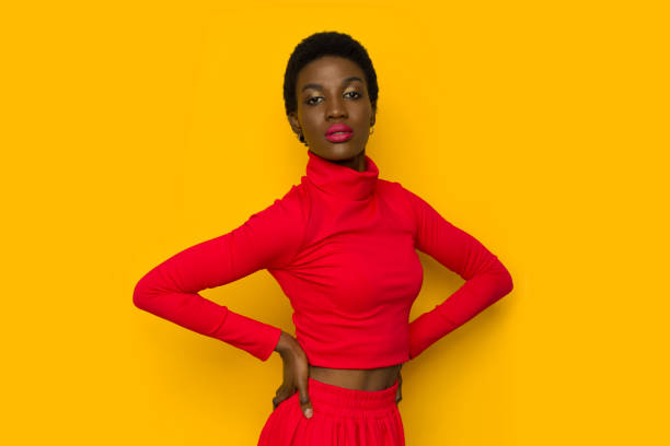 Portrait of black woman in red turtleneck sweater Portrait of black woman in red turtleneck sweater is posing with hands on hip. high collar stock pictures, royalty-free photos & images