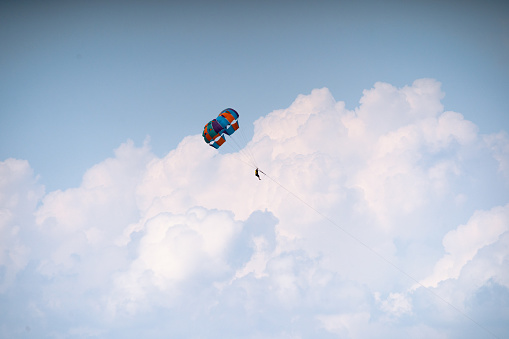 para navegar deslizándose bajo el colorido dosel de paracaídas colgando con las piernas desnudas en arnés contra un cielo nublado al atardecer en el clima ventoso que muestra deportes acuáticos de aventura en Havelock Andaman Nicobar isla India photo