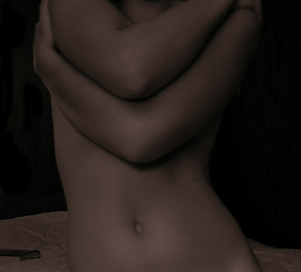 Dark image of myself, a self portrait, with my arms wrapped around my chest and my stomach showing. Very emotive.