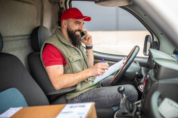 istock Delivery man sitting in delivery van and using smart phone 1390866693