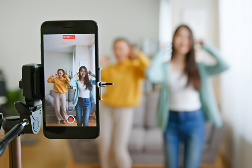 Una joven asiática con su amiga tiktoker crearon su video de baile con la cámara del teléfono inteligente juntos. Para compartir vídeo en una aplicación de redes sociales photo