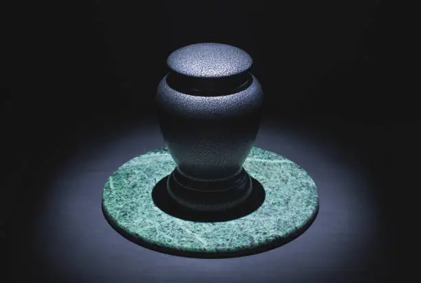 Cremation urn on marble and black. Low key image.