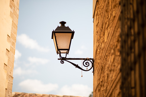 A traditional lamp hangs off the side of an old building in central Spain.