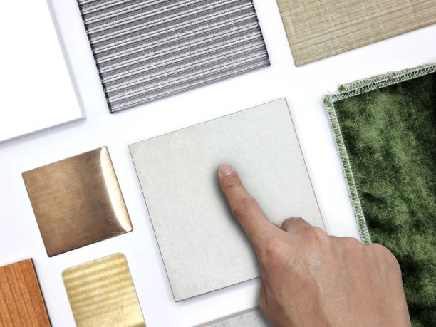 istock architect's hand pointing to samples of interior material in top view containing grey stone tiles, green velvet drapery, wooden veneer, corrugated glass, white quartz, aluminum plate for selection. 1390874308