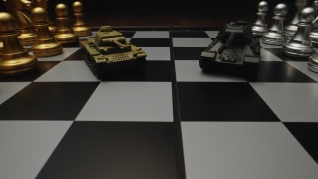 Toy tanks with chess on chessboard. Concept of military strategy.