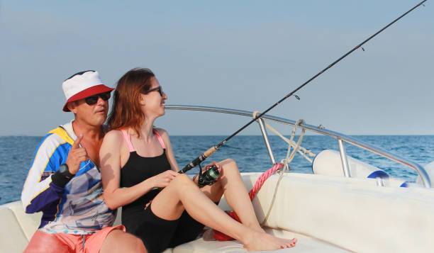 белый мужчина 45 лет и женщина 35 лет ловят рыбу на лодке. - male 30s 35 40 years 30 35 years стоковые фото и изображения