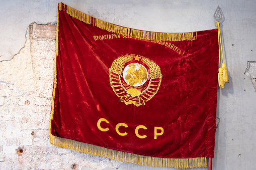 Vintage Red Flag of the Soviet Union with Golden Coat of Arms is on a grungy wall