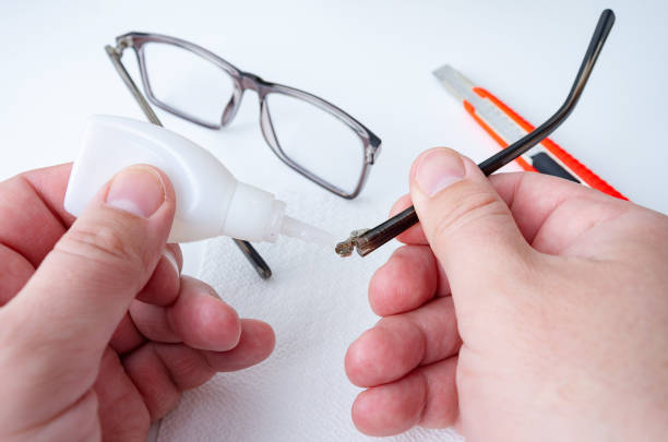 Poor man repairing eyeglasses with glue at home. stock photo