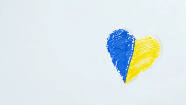 Heart shape pained in Ukrainian flag color isolated on white with copy space. Love and peace for Ukraine concept. Top view. Flat lay.