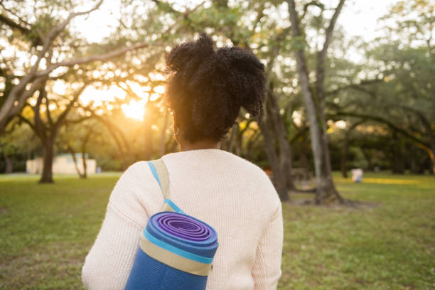 Rearview of African American Woman Walking with a Yoga Mat in the Park