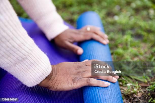 Hands of African American Woman Setting Up a Yoga Mat on the Grass