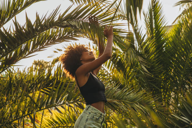 istock Pretty young afro woman among palm trees 1390881734
