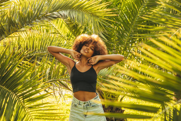 istock Pretty young afro woman among palm trees 1390881763