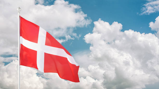 istock Danish flag on flagpole against cloudy sky 1390882737