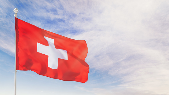 Switzerland flag on flagpole against blue cloudy sky. Panoramic image with copy space on the sky