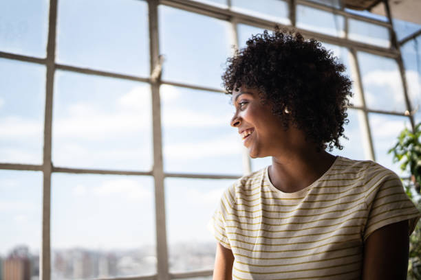 istock Contemplative young woman looking through the window at home 1390883073