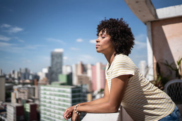 jeune femme respirant les yeux fermés sur le balcon de l’appartement - souffle photos et images de collection