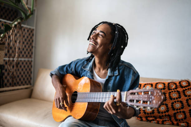 Young man playing guitar at home Young man playing guitar at home african musical instrument stock pictures, royalty-free photos & images