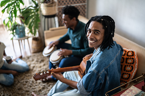 Portrait of a young man playing guitar with friends at home