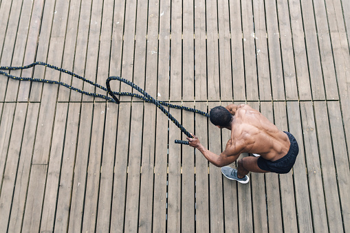 Afro American muscular man, exercising with heavy ropes. Photo of handsome man with perfect body Strength and motivation. aerial view