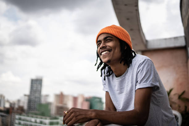 Young man looking away contemplating in the apartment's porch Young man contemplating in the apartment's porch hope stock pictures, royalty-free photos & images