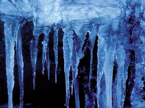 A close-up of some icicles on a winter's day. Created an almost surreal blueish color on a dark black background.