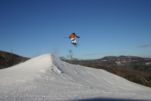 Skier at Sugarbush, Vermont jumping a spine in terrain park.