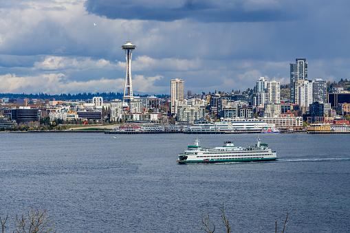 A view of the Seattle skyline with a ferry and clouds above.