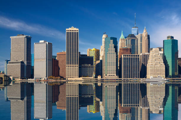 new york city skyline avec manhattan financial district, world trade center reflété dans east river et blue sky avec des nuages. - east river drive photos et images de collection