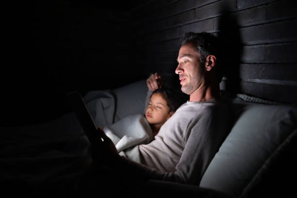 istock Father reading a bedtime story to is daughter while lying in bed 1390886900