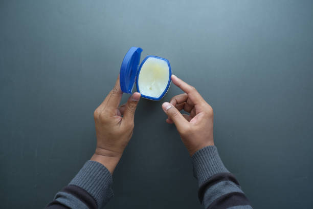 top view of man hand using petroleum jelly on black background Close up of man hand using petroleum jelly . vaseline face stock pictures, royalty-free photos & images