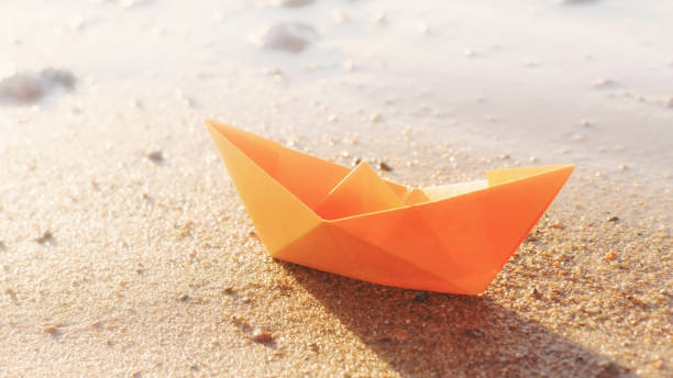 istock Orange paper boat on sandy beach outdoors 1390889332